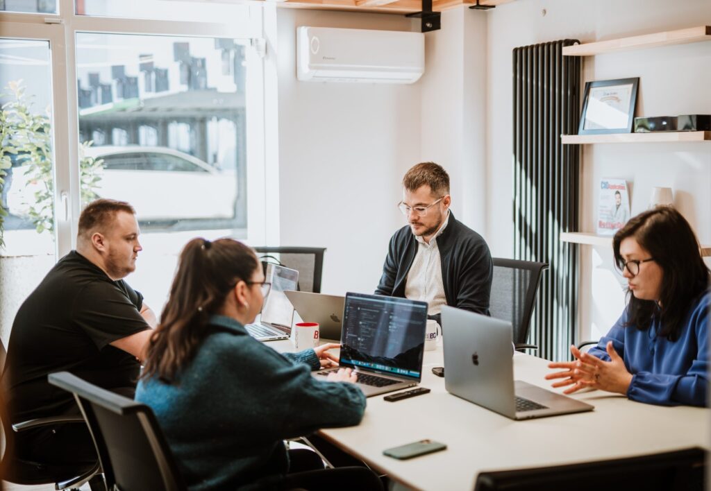Four ways teams quietly break QA independence, and what happens next Four BetterQA colleagues around a table with laptops open, one of them speaking