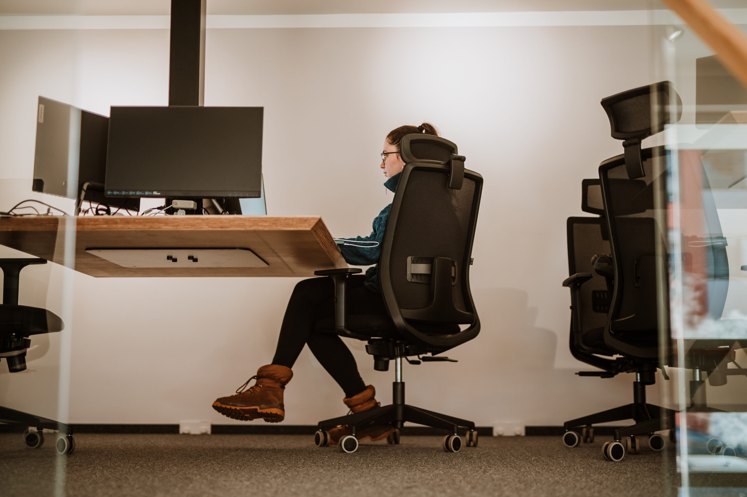 A BetterQA tester working alone at a desk, seen through a glass partition