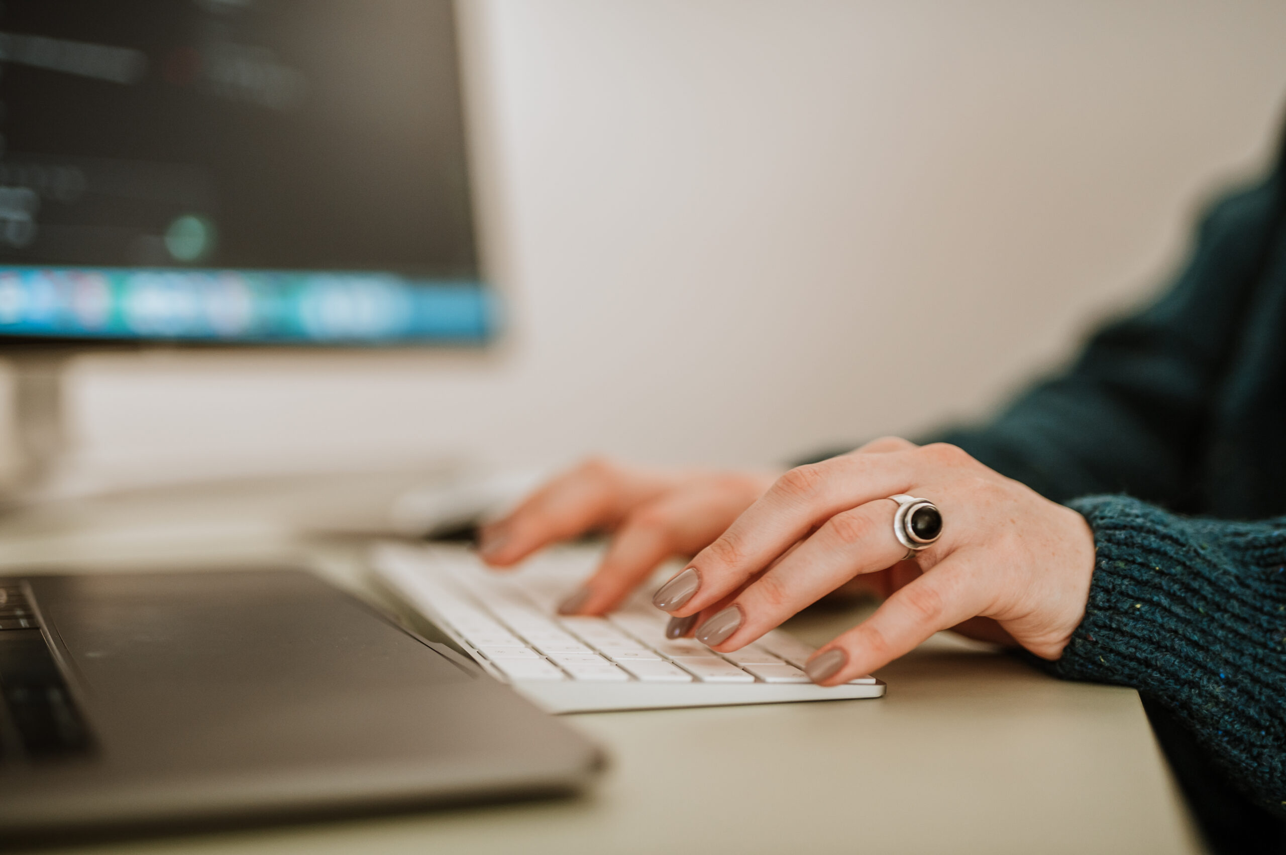 A BetterQA tester's hands on a keyboard, with test code open on the monitor behind