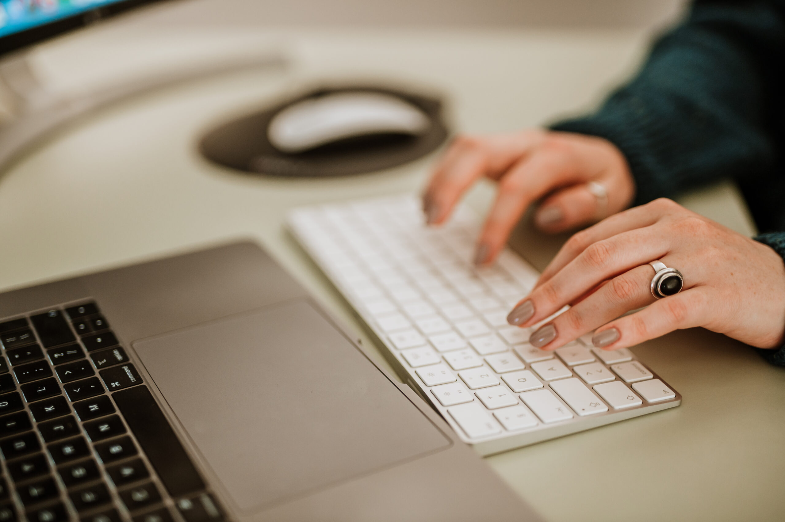 A BetterQA tester's hands typing on a white keyboard beside an open laptop