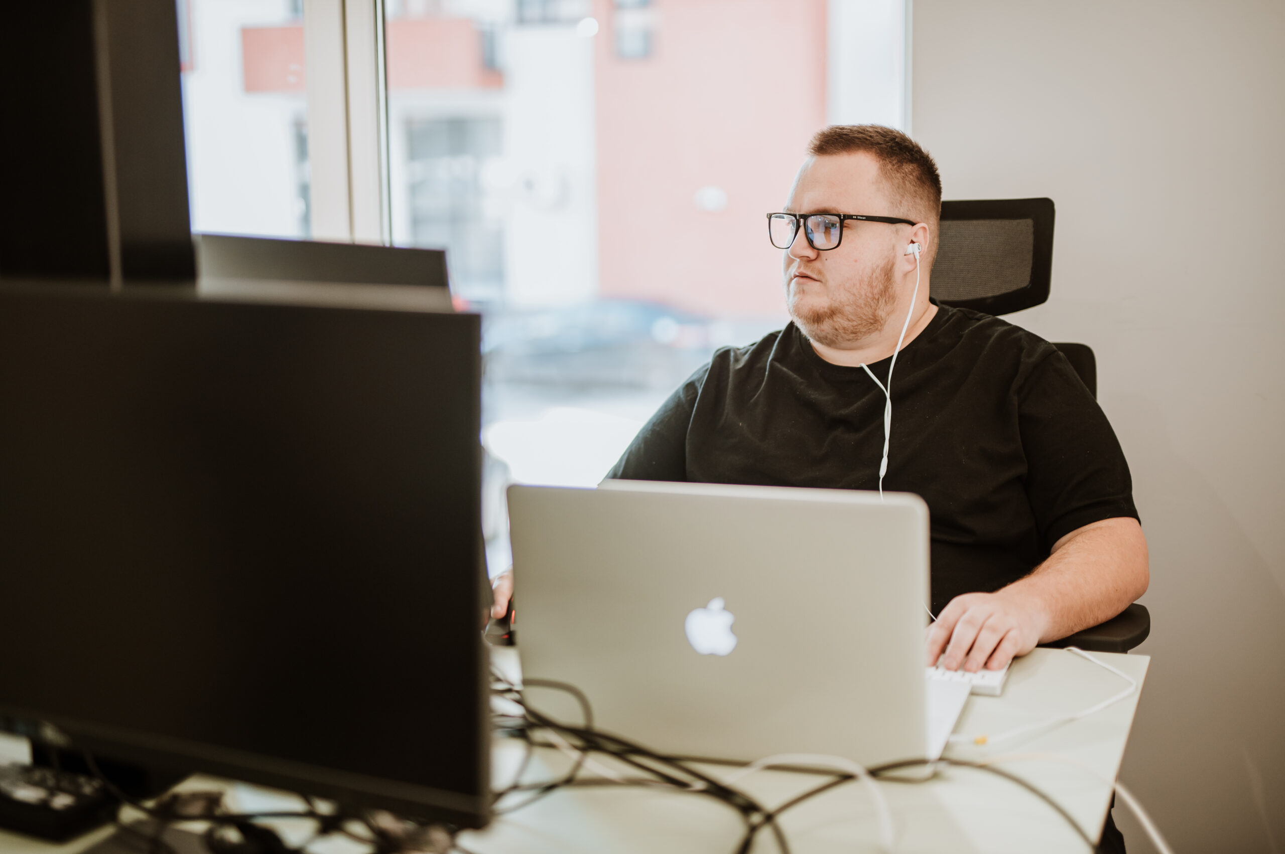 A BetterQA engineer working alone on a laptop at a desk by the office window