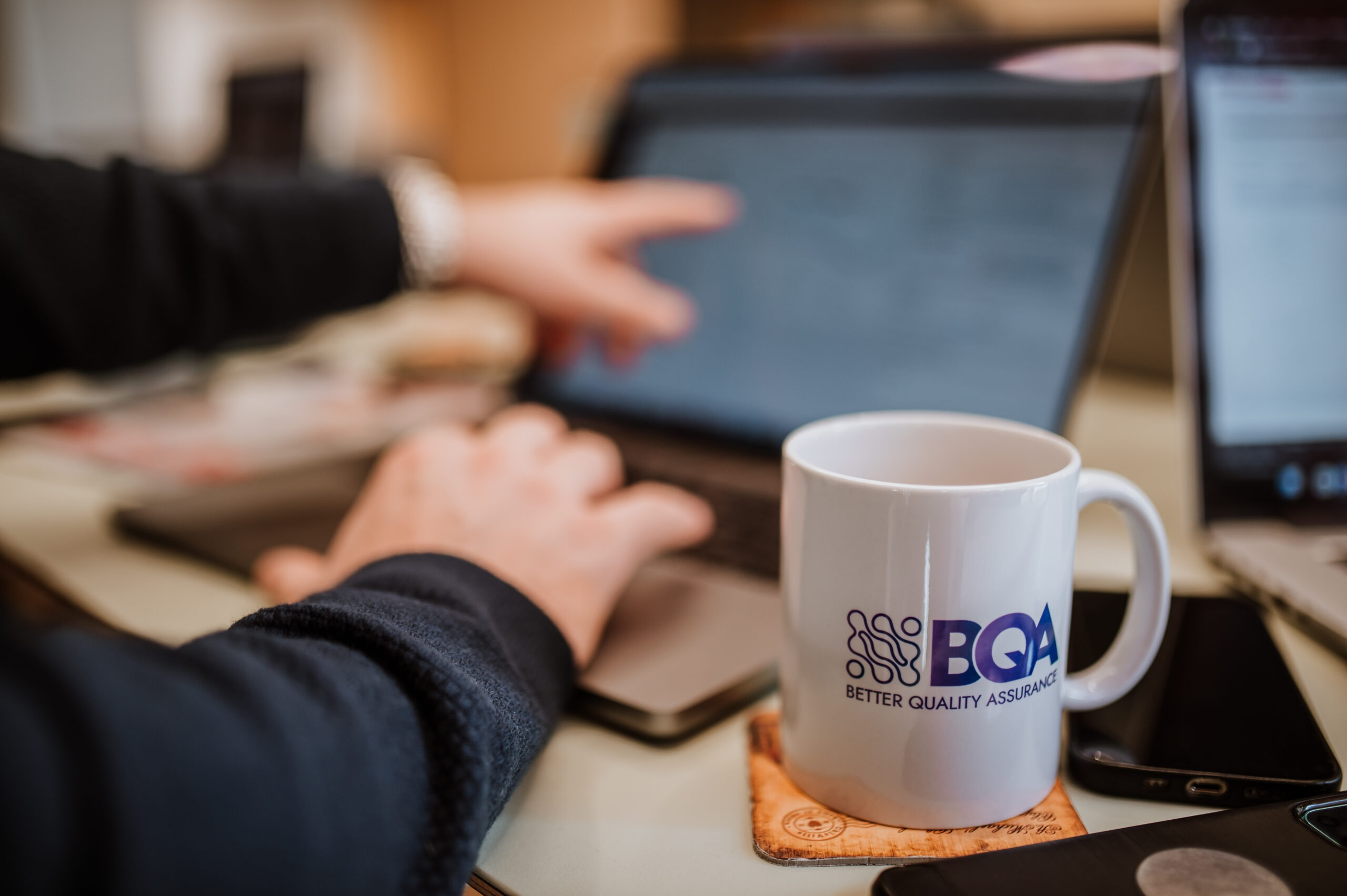 Engineer working on a laptop next to a BetterQA mug