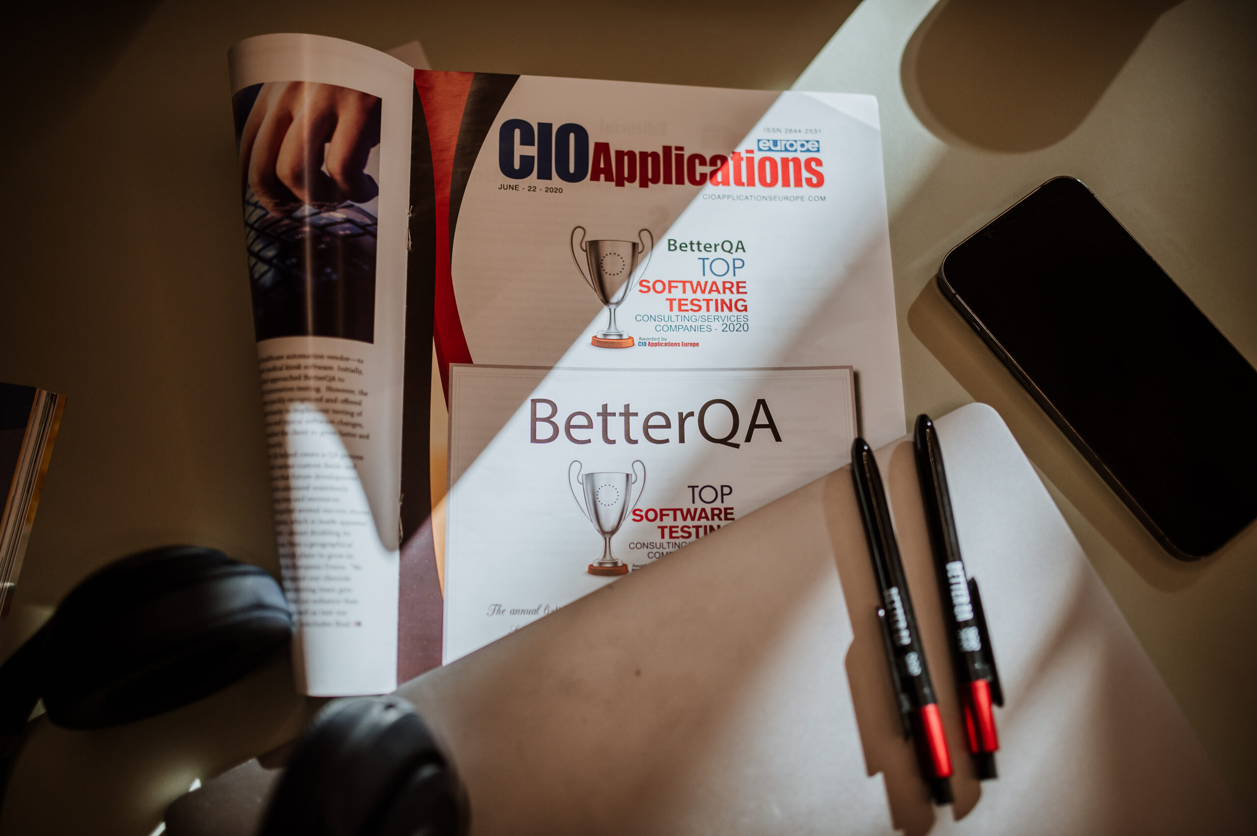 BetterQA software testing award magazine on a desk next to a laptop