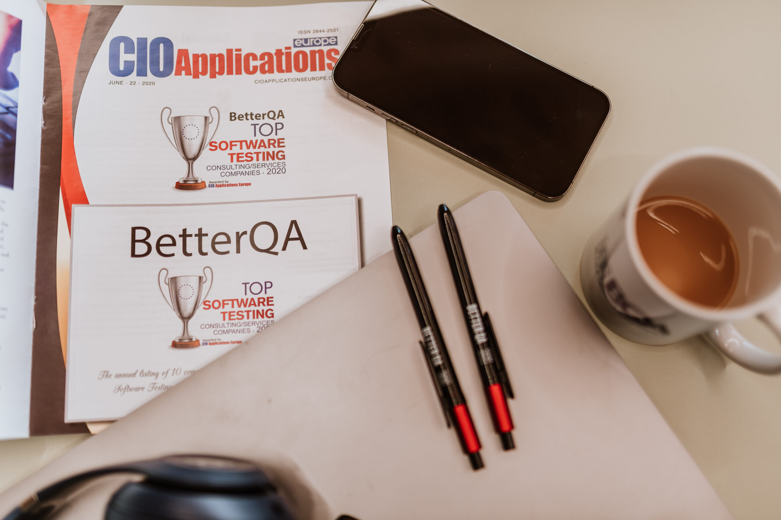 BetterQA desk with coffee, pens and an industry magazine feature