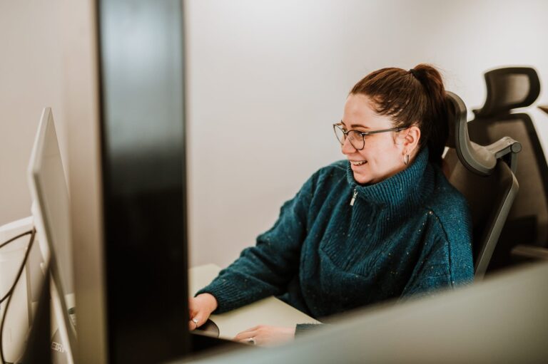 A BetterQA engineer smiling as she works at her desk in the Cluj office