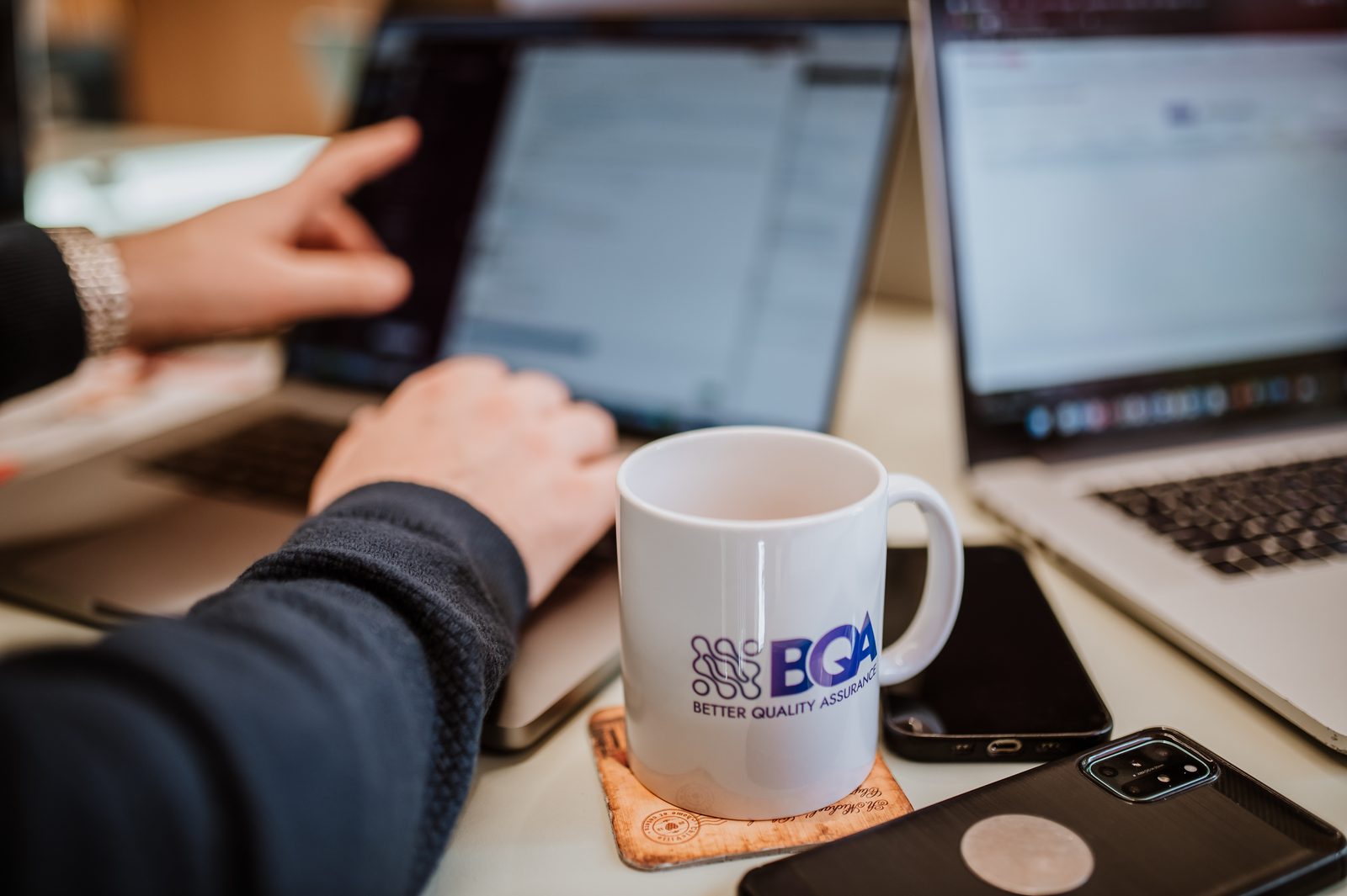 A BetterQA engineer working on a laptop next to a BetterQA mug in the Cluj-Napoca office